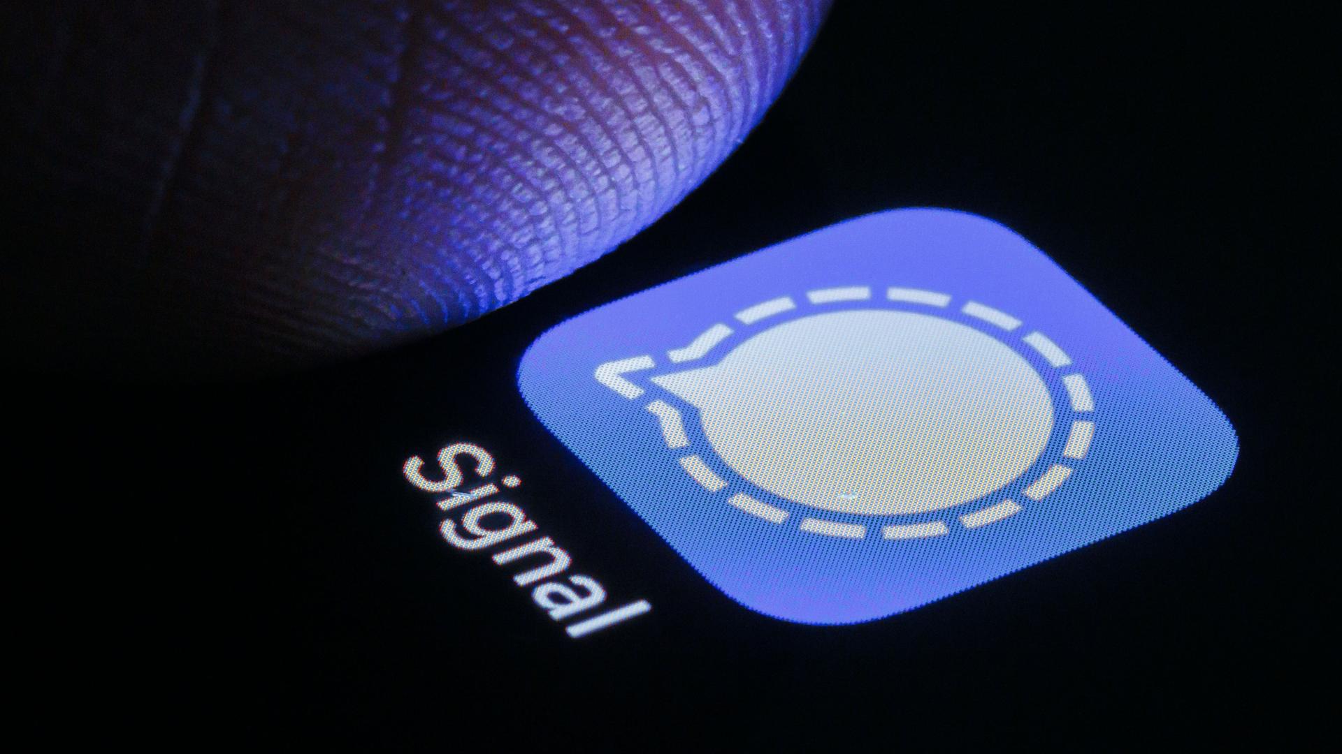 Nahaufnahme eines Fingers, der auf einem Smartphonescreen auf die Signal-App tippt.