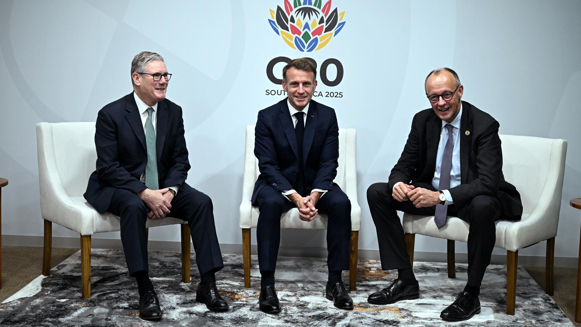 Der britische Premierminister Keir Starmer (links), Frankreichs Präsident Emmanuel Macron (Mitte) und Bundeskanzler Friedrich Merz lächeln für die Kameras beim G20-Gipfel in Johannesburg