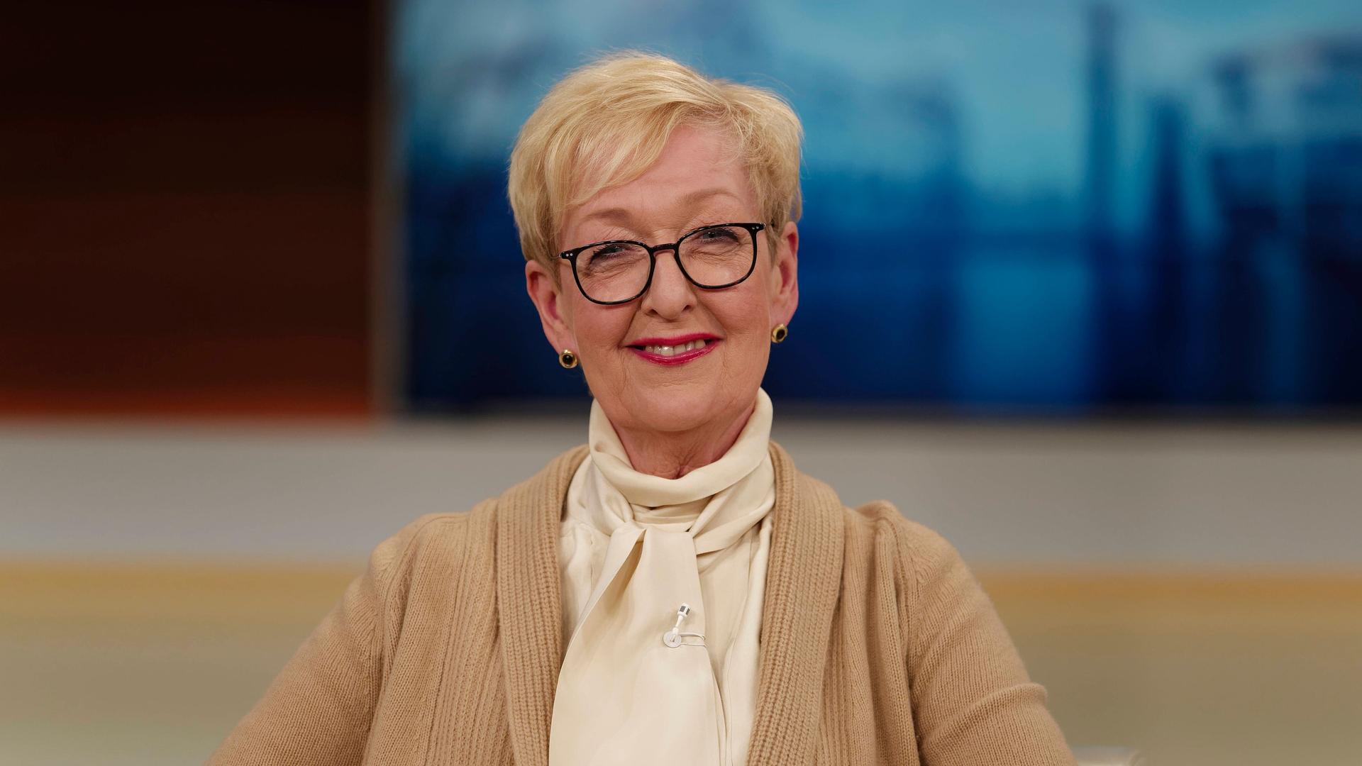 Stefanie Babst in einer Talkrunde bei Anne Will. Sie trägt beige Kleidung und schaut in die Kamera. Im Hintergrund ist das Blau des Studios zu sehen.