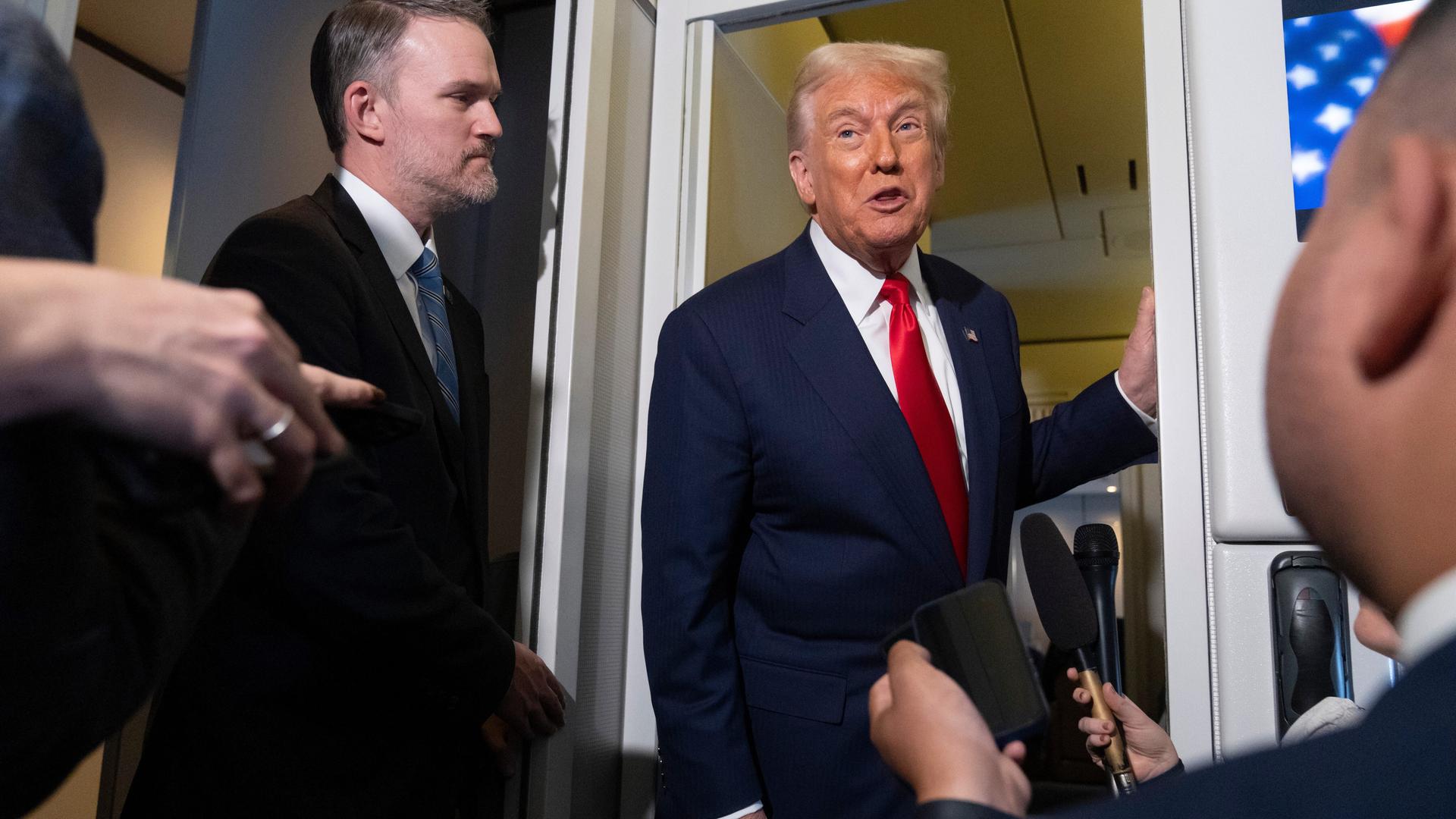 US-Präsident Donald Trump lehnt an der Tür der Regierungsmaschine Airforce One im Gespräch mit Reportern am 30.10.2025