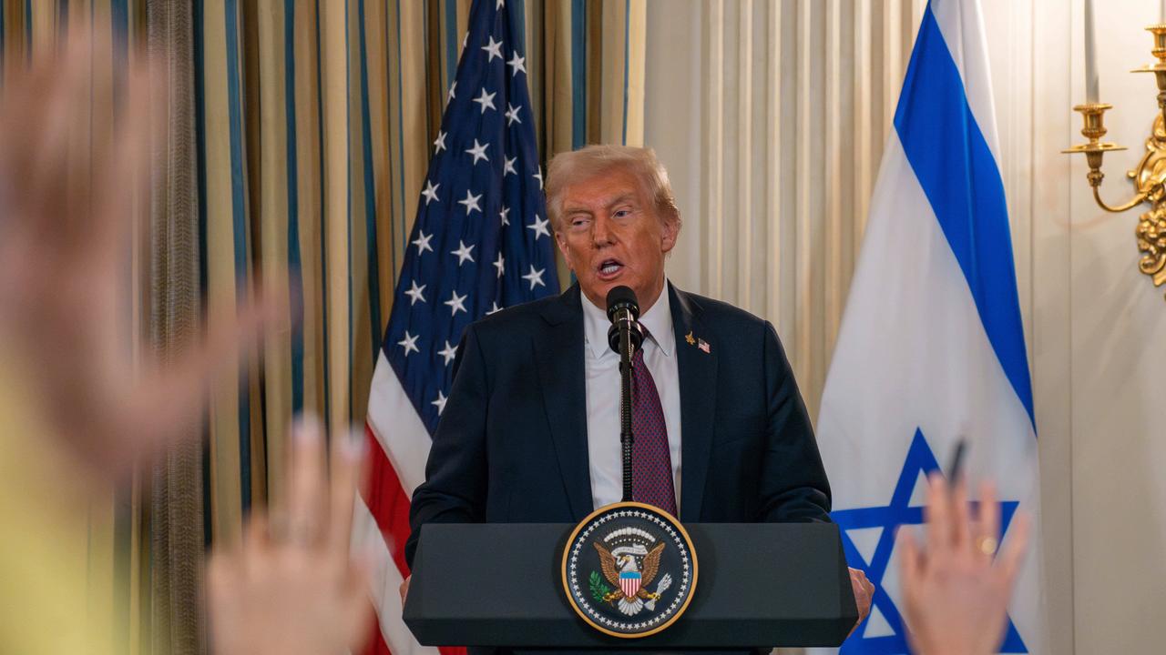 Donald Trump am Rednerpult. Im Vordergrund sieht man verschwommene erhobene Hände von Journalisten.