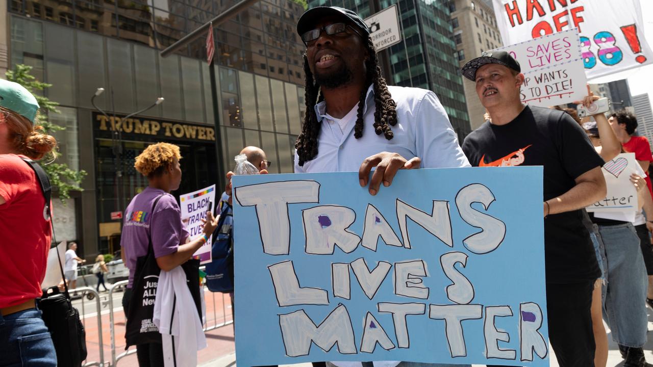 "Trans Lives Matter": In Anlehnung an den ikonischen Slogan "Black Lives Matter", der nach dem Tod von George Floyd bekannt wurde, hält ein Mann mit Rastalocken ein hellblaues Schild Richtung Kamera. 