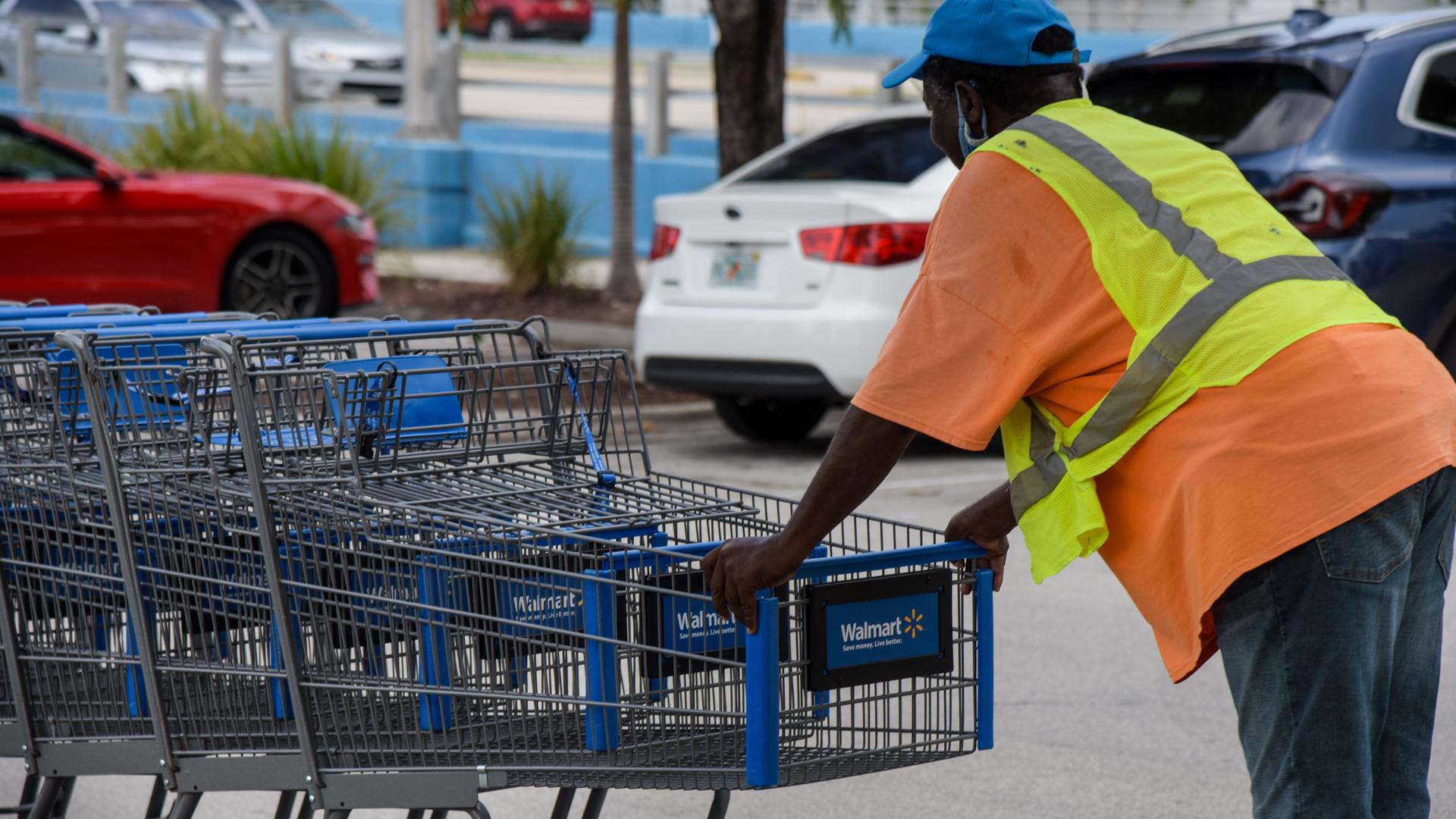 Ein Walmart-Mitarbeiter in Florida schiebt Einkaufswägen über einen Parkplatz.