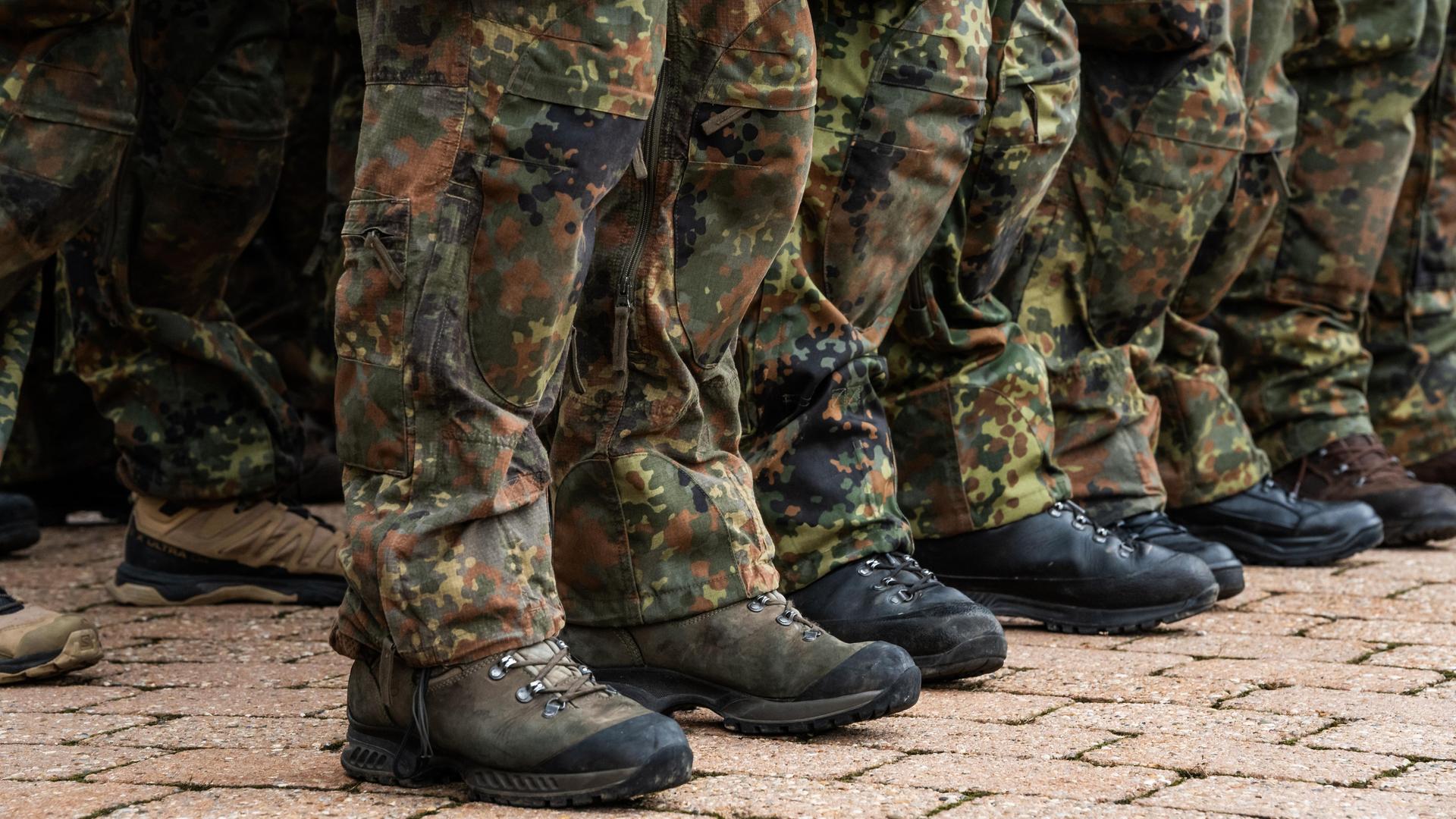 Zu sehen sind die Füße von Soldaten der Bundeswehr in Tarnuniform, die in einer Reihe stehen.