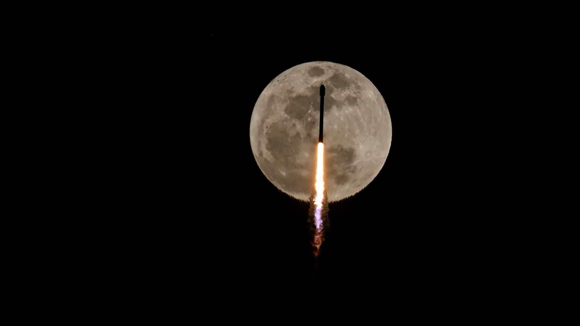 Eine SpaceX-Rakete vor dem Mond. Sie bringt Satelliten in die Erdumlaufbahn.