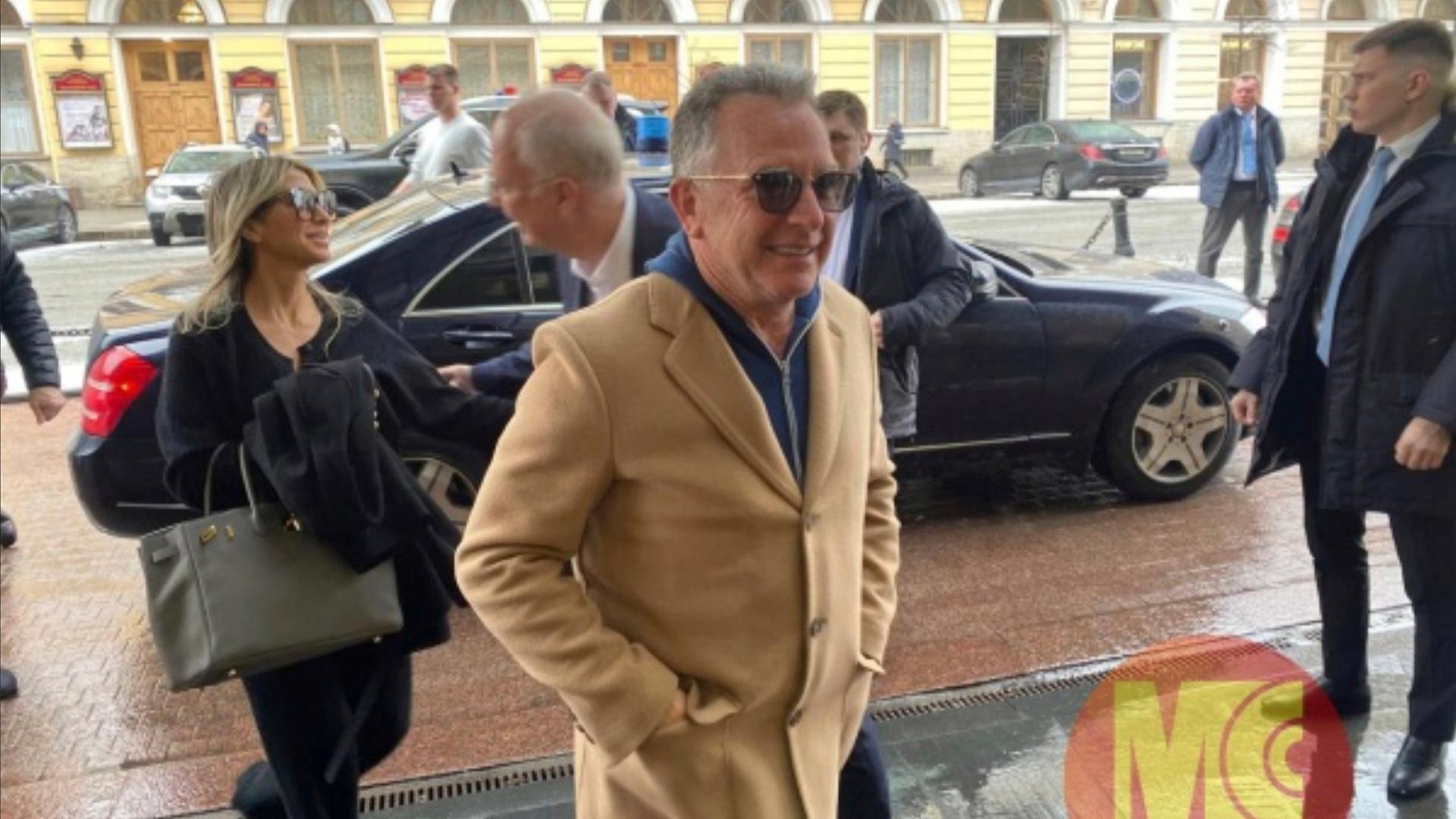 Witkoff und mehrere Teilnehmer seiner Delegation gehen von einem Auto weg auf den Betrachter zu. Witkoff trägt einen braunen Mantel und eine Sonnebrille. Er lächelt. 